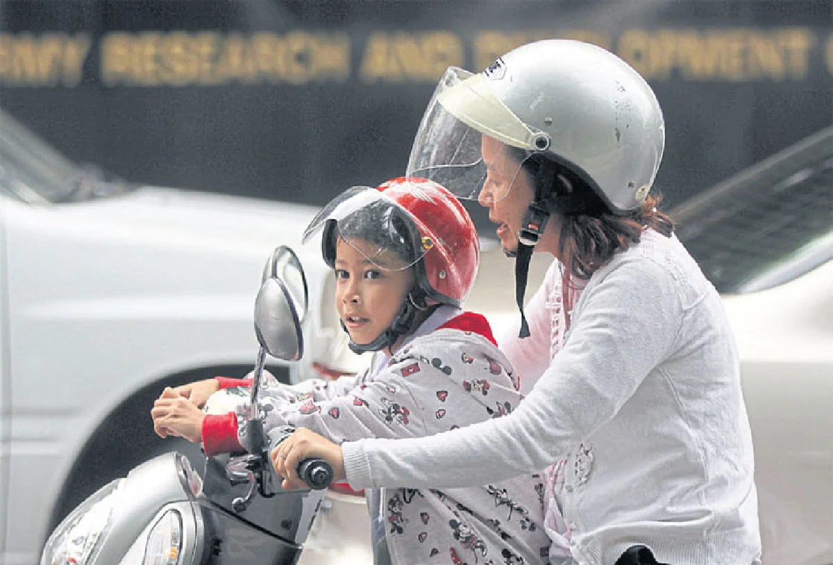 เด็กไทยซ้อนท้ายใส่หมวก