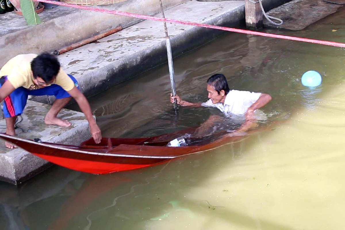 ผู้ค้าตลาดน้ำดำเนินสะดวกฉลองปีใหม่แข่งพายเรือด้วยมือ