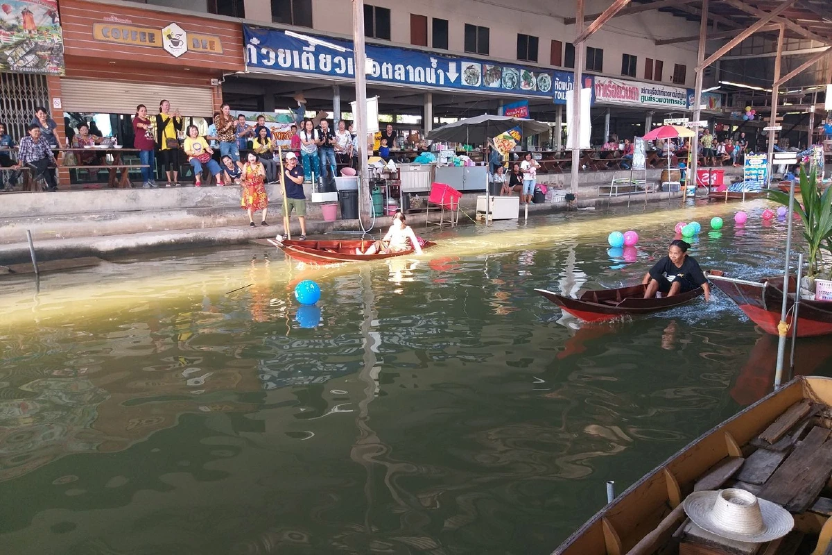 ผู้ค้าตลาดน้ำดำเนินสะดวกฉลองปีใหม่แข่งพายเรือด้วยมือ